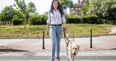 Usuaria ciega cruzando la calle con su perro guía