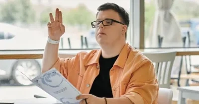 Un joven con síndrome de Down en un restaurante levanta la mano