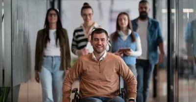 Una persona en silla de ruedas a compañada de otras personas