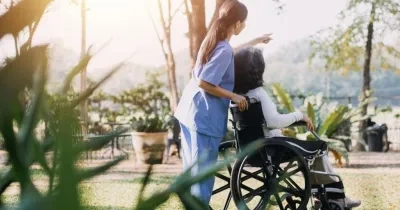 Una persona en silla de ruedas con una persona cuidadora