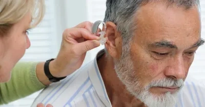 Una señora poniendo un audífono a un señor