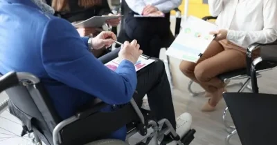 foto de una persona en silla de ruedas con unos documentos en las piernas durante una reunión