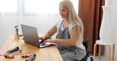 mujer ocn discapacidad trabajando con su ordenador portátil en la mesa