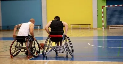 personas con discapacidad jugando a baloncesto en silla de ruedas en un centro deportivo adaptado