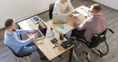 Tres personas trabajando juntas, una de ellas en silla de ruedas (Fuente: Servimedia)
