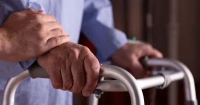 Primer plano de las manos de un hombre mayor sosteniendo un andador