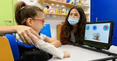 Una niña con discapacidad con un juguete adaptado y su tutora al lado (Fuente: Irisbond)
