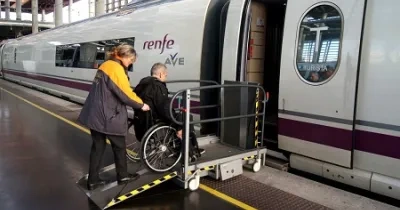 hombre en silla de ruedas subiendo al tren con la ayuda de una trabajadora de Renfe