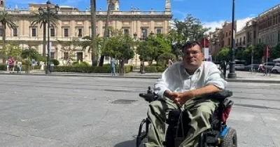Carlos Reina Rosales, de 35 años y uno de los participantes en este estudio, sentado en su silla de ruedas eléctrica, frente a un museo en el centro de Sevilla (Fuente: Jonas Bull/Human Rights Watch)