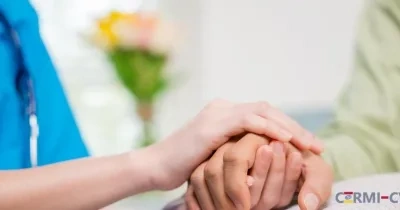 Las manos de una sanitaria cogen las de un paciente