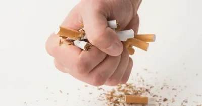 un puño cerrado con tabacos en la mano aplastándolos y rompiéndolos