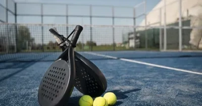 raquetas de padel de pies, junto a pelotas y al fondo la pista de padel