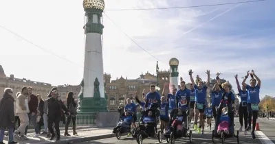 Maratón del equiipo Zurich AEFAT por San Sebastián con corredores y los chicos en silla de ruedas siendo ovacionados por los espectadores a la izquierda