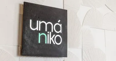 Cartel de Umaniko en negro sobre una pared en solor beige