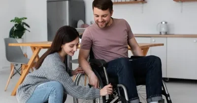 Mujer sin discapacidad ayudando a frenar la silla de un chico en silla de ruedas