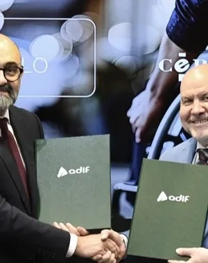 Los dos representantes firmando el acuerdo mientras se dan la mano 