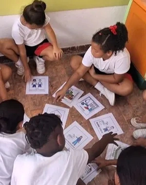 Varios alumnos en círculo mientras juegan y aprenden con pictogramas en el centro
