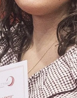 una alumna en silla de ruedas con un certificado en la mano, detras ptras personas con el logo de fundación once