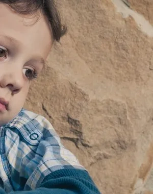 Un niño sentado apoyado en un muro