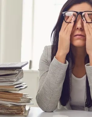 Mujer llevándose las manos a los ojos debido al agotamiento visual del trabajo