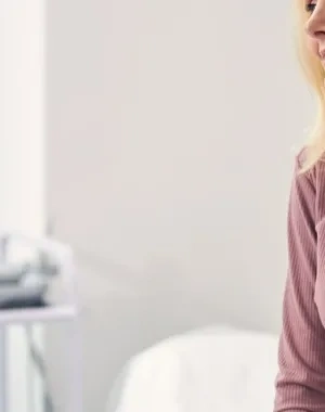 Persona sentada en una consulta médica conversa con un profesional sanitario. Ambos aparecen en una sala de exploración luminosa, con equipamiento clínico al fondo, en una escena relacionada con el asesoramiento y seguimiento de la salud durante la menopausia.