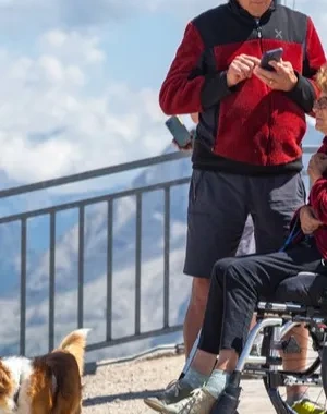 Una pareja con su perro, ella en silla de ruedas, disfrutando de un turismo en la montaña