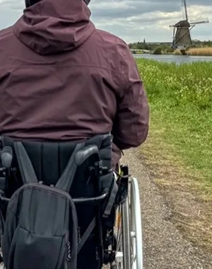 Persona en silla de ruedas de espaldas mientras camina al frente por un sendero