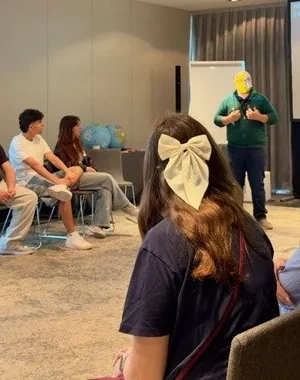 Varios jóvenes disfrutando de un coloquio, en círculo delante de los ponentes