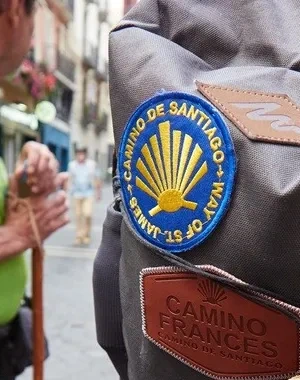 un peregrino durante el Camino de Santiago con un chaleco reflectante y una mochila