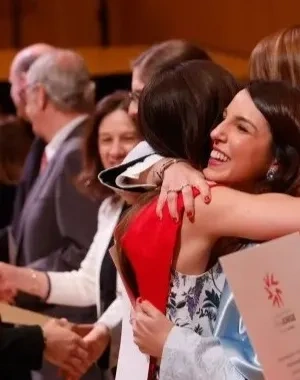 Una foto de dos alumnos recibiendo el título de los profesores de la universidad y dándose un abrazo