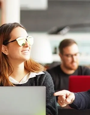 Tres personas hablando delante de la pantalla de un ordenador en la oficina