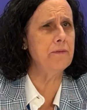 Ana Peláez delante de un micrófono en una sala de prensa, con un fondo azul de logos a su espalda