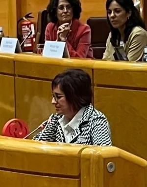 Mujer dando una conferencia en un estrado de un hemiciclo