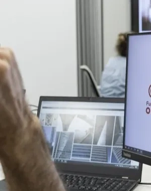 Un hombre con gafas mirando a la pantalla de un ordenador donde sale el logo de por talento digital y fundación once