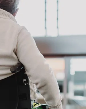 Un hombre con silla de ruedas, al que se ve de espaldas, movíendose por el aeropuerto con su maleta