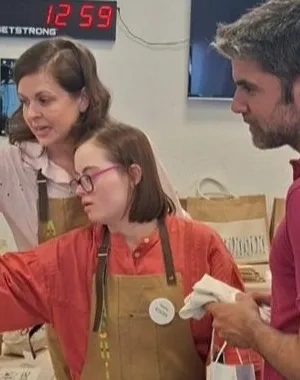 Dos profesores atendiendo a una alumna del CEE ACHIRA, enseñándola a vender en el mercadillo