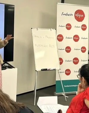 Dos profesores dando una explicación a sus alumnas, que están sentadas en sus pupitres