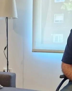 Una mujer sentada en un sofá hablando con una persona en silla de ruedas