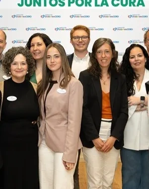 Veinte personas posando para la foto junto delante de la pantalla digital donde se proyectan diapositivas del encuentro