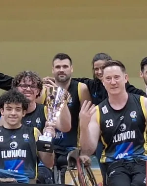 Equipo y cuerpo técnico del CD Ilunion posan en una pista cubierta de baloncesto tras proclamarse campeones de la Supercopa de España de baloncesto en silla de ruedas. En el centro de la imagen, varios jugadores en silla de ruedas sostienen un trofeo y realizan un gesto con cuatro dedos levantados. En la parte frontal aparecen paneles con los logotipos de Fundación ONCE, BSR España y un cartel con la palabra “CAMPEÓN”. Al fondo se observan canastas y pancartas institucionales de Castilla-La Mancha y BSR Esp