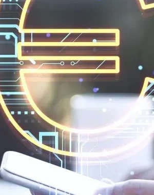 Mano sosteniendo un teléfono móvil junto a un ordenador portátil, con un símbolo del euro digital superpuesto en el centro de la imagen. La escena representa conceptos relacionados con pagos electrónicos, finanzas digitales y tecnología financiera. Fondo desenfocado con tonos claros y elementos tecnológicos.