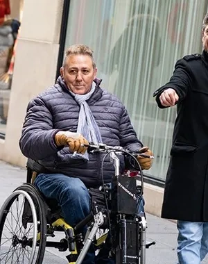 Un asistente personal al lado de un hombre en silla de ruedas