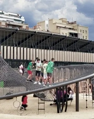 Un parque con niños jugando en él y sus padres sentados en el banco