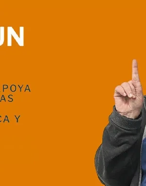 Hombre sonriente levantando el dedo índice frente a un fondo naranja en la campaña “Mueve un Dedo” de COCEMFE.