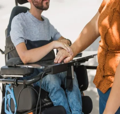 Persona en silla de ruedas junto a cuidadora 