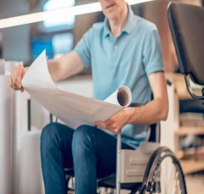 Un hombre en silla de ruedas con unos documentos en la mano