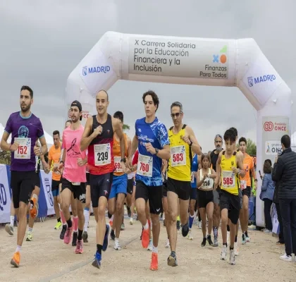 Salida de la X Carrera Solidaria por la Educación Financiera y la Inclusión en el Parque Forestal de Valdebebas (Madrid), con decenas de corredores atravesando el arco de meta de una prueba organizada por ASNEF y Fundación ONCE.