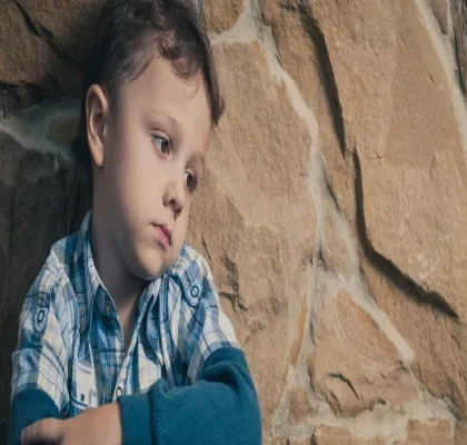 Un niño sentado apoyado en un muro