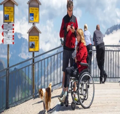 Una pareja con su perro, ella en silla de ruedas, disfrutando de un turismo en la montaña