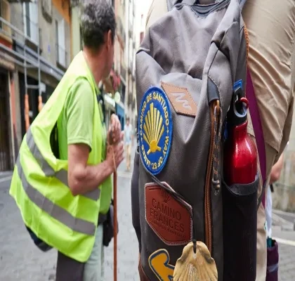un peregrino durante el Camino de Santiago con un chaleco reflectante y una mochila